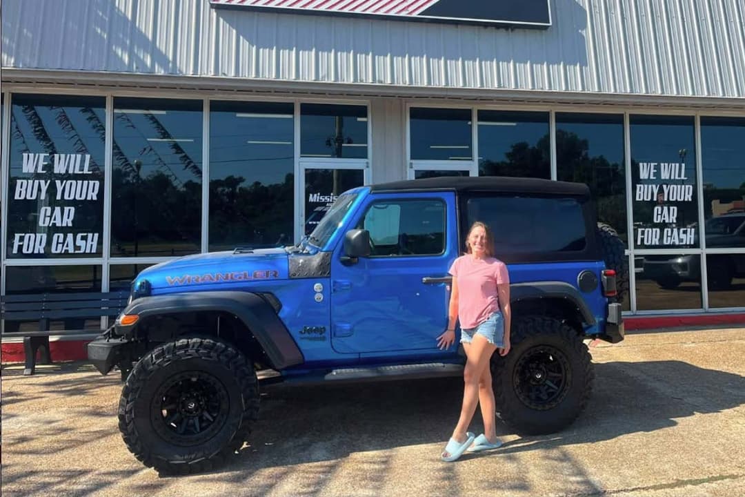 Customer beside a blue Jeep at the dealership