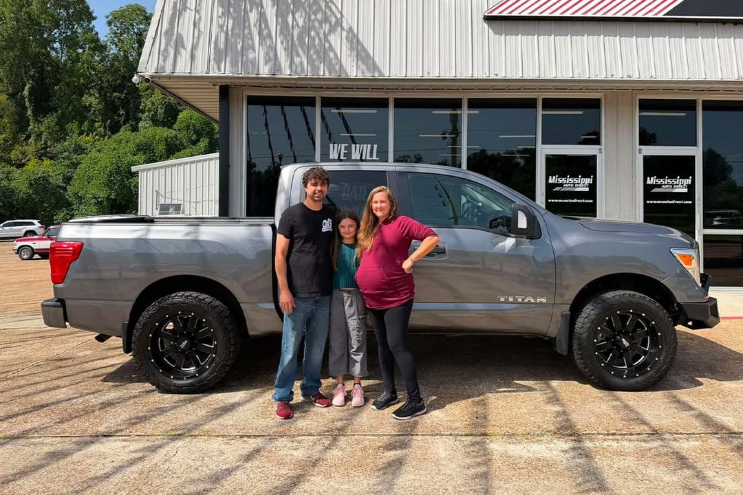 Family beside a gray pickup at the dealership